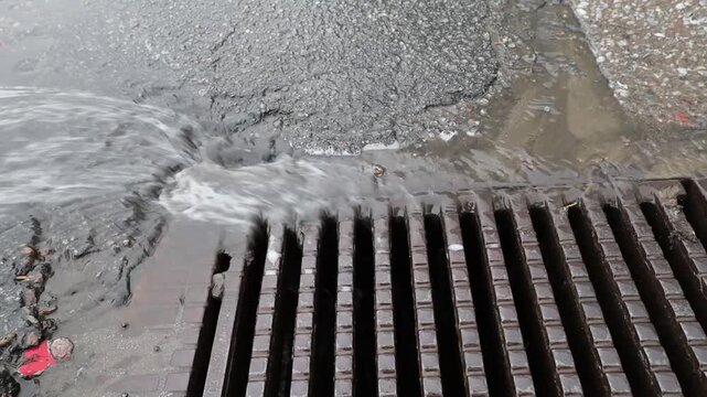 Stockholm, Sweden Heavy rain falls on a street and runs down a storm drain. 