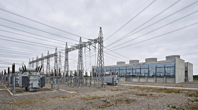 High-voltage electrical substation with transformers and transmission towers next to a modern data center