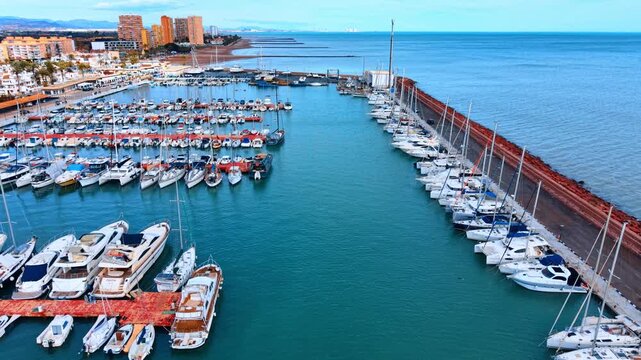 Drone view of harbor entrance and stone breakwater. Perspective aerial shot of a yacht port leading to the open sea with protective breakwater and horizon.