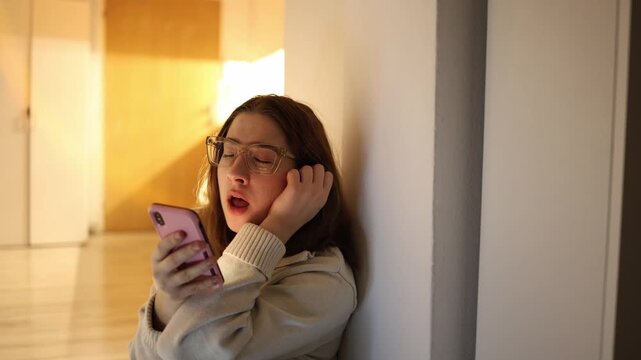 Woman sitting on floor at home scrolling smartphone looks bored and tired yawning from passive content consumption showing low energy procrastination and digital fatigue