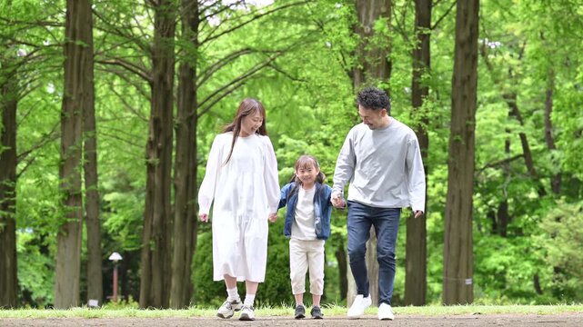 家族、新緑の公園で手を繋ぐ歩く幸せなファミリーライフスタイル　全身の動画スローモーション