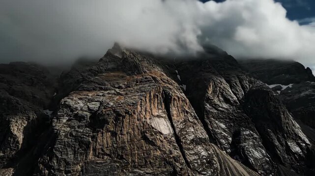 Dramatic dark mountain peaks shrouded in ominous clouds while showcasing rugged terrain and a sense of wild natural beauty with snow patches and rocky textures