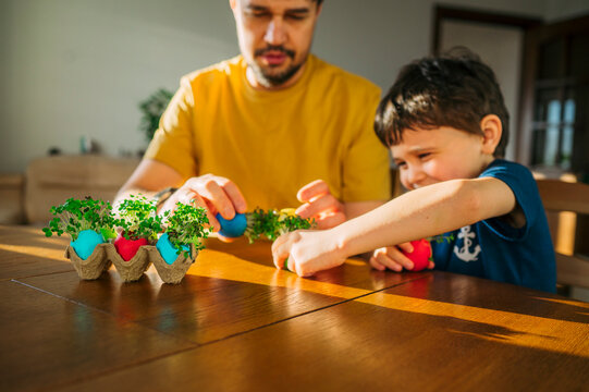 Smiling father and son making fresh easter egg decor indoors