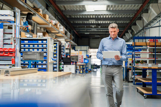 Manager using tablet walking in production hall
