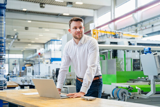 Manager using laptop in modern production hall