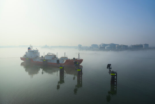 Oil tanker and storage tanks in morning fog at Rotterdam harbour