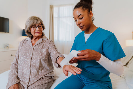Healthcare professional wrapping bandage on senior at home