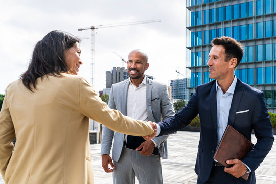 Real estate agents shaking hands outdoors in the financial district
