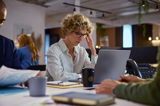Stressed mature businesswoman working late at night