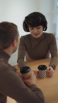 Two People Engaged in a Friendly Conversation While Enjoying Coffee at a Modern Cafe