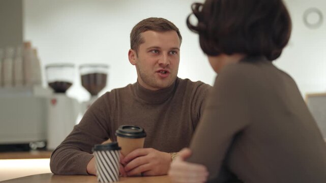 Young Man and Woman Engaged in Pleasant Conversation Over Coffee in a Modern Cafe