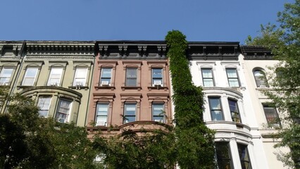 Fototapeta premium New York City townhouse buildings, brownstone row houses in Manhattan or Brooklyn, United States of America. Classic buildings on residential district street. Real estate property. Rowhouse townhome.