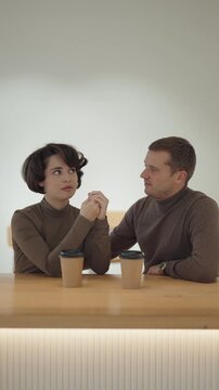 A Couple Shares a Tender Moment Holding Hands During an Intimate Coffee Shop Conversation