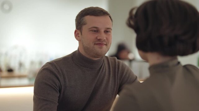 Smiling Man Engaged in a Pleasant Conversation with a Woman in a Bright Cafe Setting
