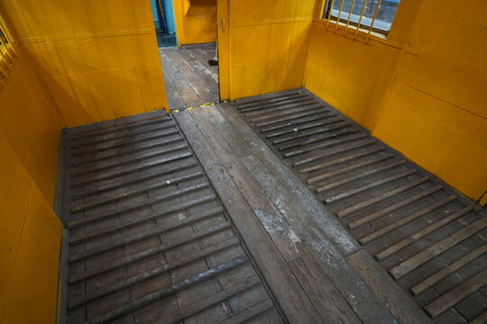 Interior of vintage yellow cargo train with wooden floor.