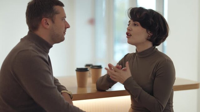 Two People Engage in an Animated Conversation While Enjoying Coffee in a Modern Setting