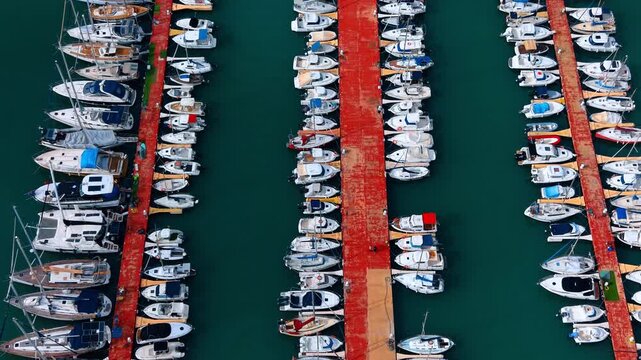 Aerial top down perspective of white boats at dock. High resolution top view of diverse white yachts and catamarans docked at a harbor pier.