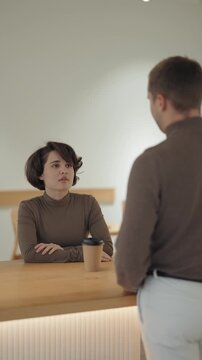 Young Woman Engages in a Focused Conversation with a Man at a Modern Cafe Setting