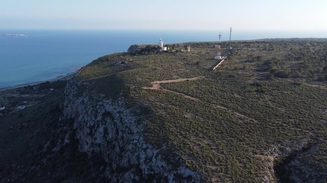 Lighthouse atop the cliff, with Tabarca Island in the background. Santa Pola, Spain.