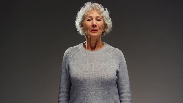 Portrait: senior gray haired woman relaxing, take a deep breath. Retired female breathing deeply, smiling looking at camera. Mature old female enjoys air. Healthy calm nervous system, well-developed