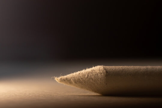 Extreme macro shot of a professional white paper blending stump tip, showcasing the fine fibrous texture and soft material used for charcoal drawing.