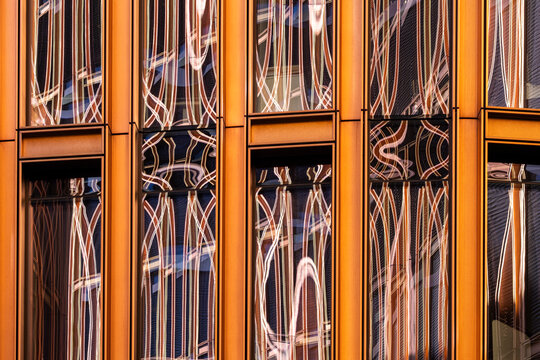 Contemporary building glass reflection on architecture facade with orange abstract lines pattern and distortion creating modern graphic texture background