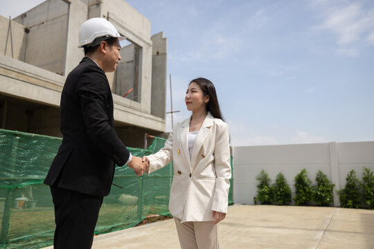 Construction project manager meets client at building site to discuss project progress and timeline updates