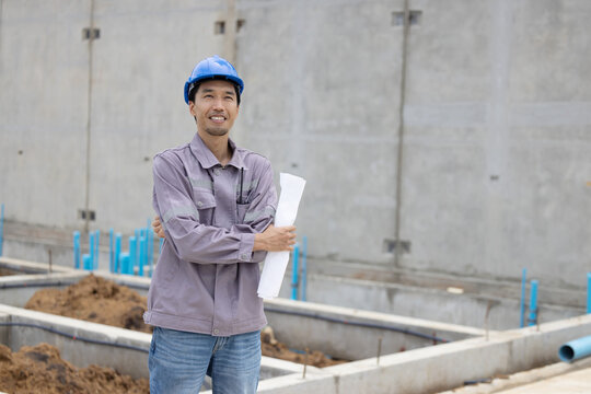 A construction manager in a safety helmet inspects a building site