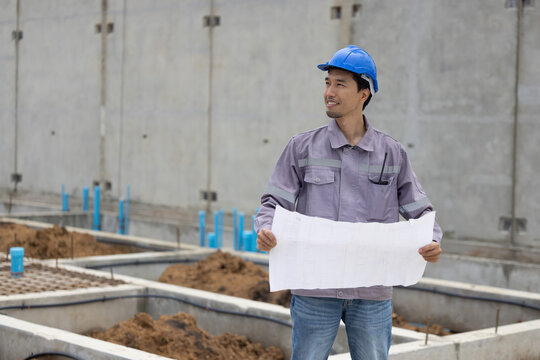 A construction manager in a safety helmet inspects a building site