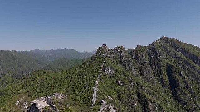 Wild unrestored Great Wall winding along mountain ridge with watchtowers and vast landscape, China