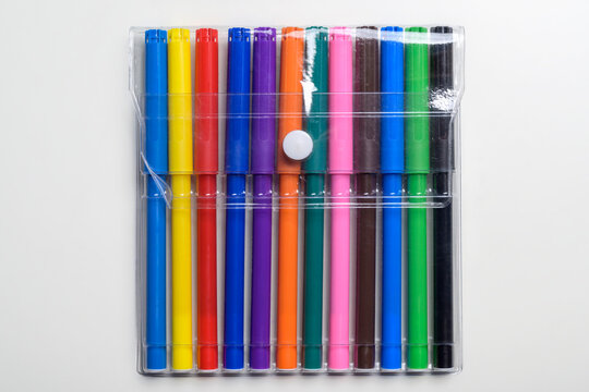 A collection of twelve vibrant multi-colored felt-tip markers in a transparent plastic pouch with a white button snap, isolated on a clean white background