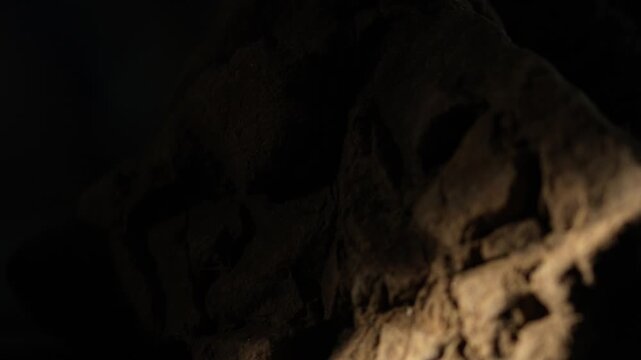 Sunlight beam moving across rugged rock peak with deep shadows