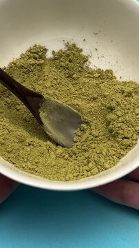 Woman holds white plate with henna and basma powder closeup