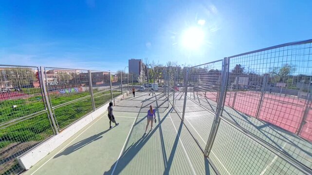 Young friends playing pickleball match outdoors on a sunny day