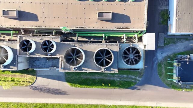 Aerial view of industrial cooling system with large fans and green ventilation units on a factory roof, showcasing continuous airflow and operational efficiency in a manufacturing environment