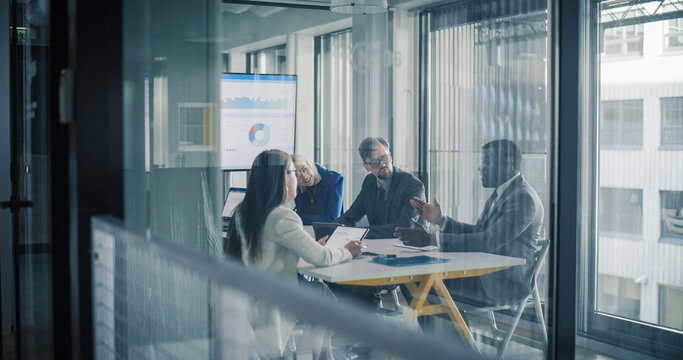 Business Leaders Sit in a Glass Meeting Room Reviewing Digital Dashboards, Discussing Performance Metrics, Setting Priorities, and Planning Strategy to Improve Sales, Marketing, Finance, Customers