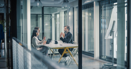 Two Business Professionals Sit Across a Table in a Glass Office, Discussing Project Goals, Reviewing Performance Dashboards, Clarifying Requirements, Managing Risk, Agreeing on Governance Structure © Gorodenkoff