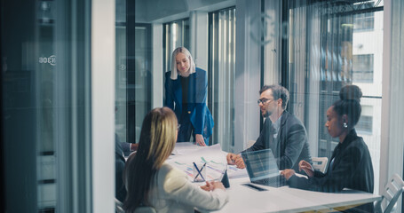 Business Manager Leads a Focused Planning Meeting in a Glass Office, Guiding a Diverse Team as They...