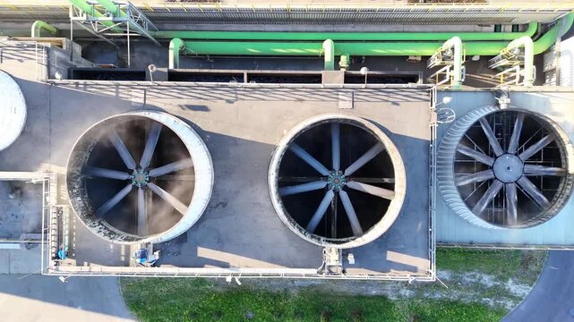 Aerial view of industrial cooling system with large fans and green ventilation units on a factory roof, showcasing continuous airflow and operational efficiency in a manufacturing environment