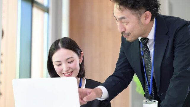パソコン業務を指導する上司と社員のOJT研修などの社員教育のイメージ　先輩に指導を受ける若手社員の成長と教育のビジネスシーンの動画クローズアップ