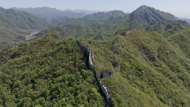Wild Great Wall winding along forested mountain ridge with remote valleys and rugged landscape, China