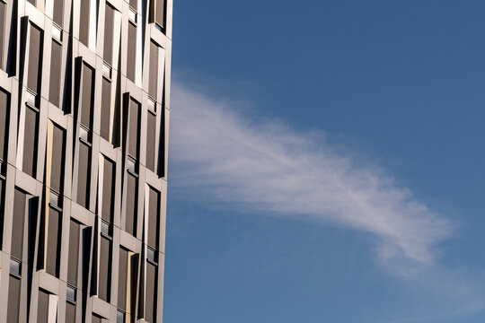 Blue sky and cloud frame modern minimal architecture facade where geometric windows detail creates clean contemporary background for branding layouts