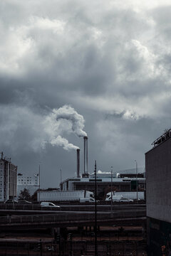 Chimney and plume above a Paris industrial plant beneath clouds where urban smoke signals energy production and heavy infrastructure