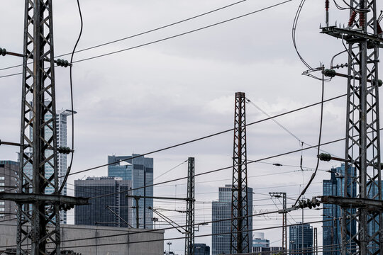 Rail wires crossing an overcast Frankfurt industrial urban city scene with towers and layered infrastructure shaping a transport corridor