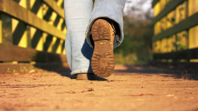 Foot in boots walking across narrow wooden bridge