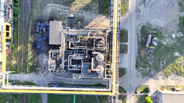 Aerial view of industrial plant showing continuous operations with pipelines, storage tanks, and machinery in a green landscape, highlighting the interconnected processes of manufacturing and producti