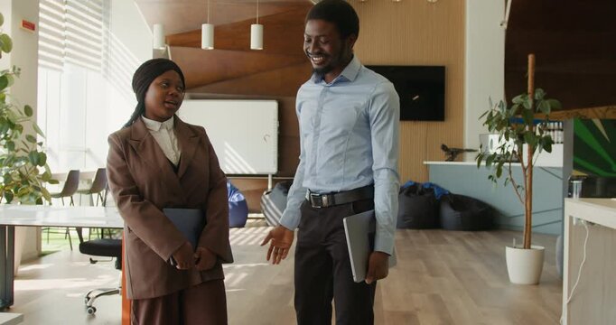 Black manager explaining plan to black colleague in coworking office