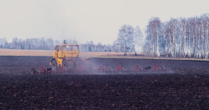 A yellow tractor plows the field. The contrasting colors of soil and crop form a stunning tapestry, illustrating the harmony between man and the land in agriculture. Modern farming. 4k video.