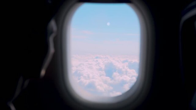 Airplane passenger looking through aircraft window over soft cloudscape during high altitude flight. Travel lifestyle aviation journey with serene sky horizon and sunlight atmosphere above clouds
