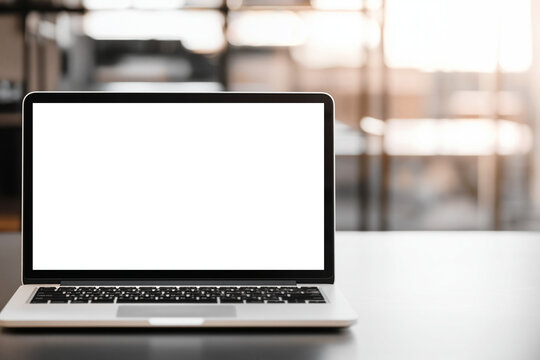 Laptop computer with blank white screen on table in modern office setting with blurred background and black keyboard